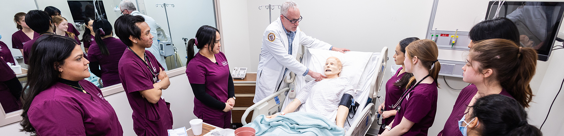 A faculty member instructs students in the sim lab